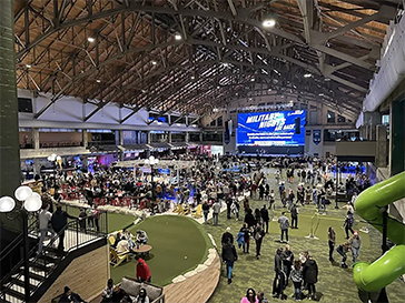 Aerial view of large crowded venue with astroturf and giant screen.
