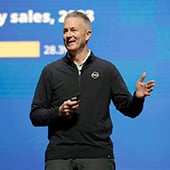 Smiling man on stage in front of screen